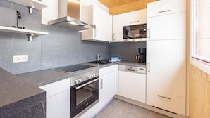 A modern kitchen with white cabinets, a stainless steel range hood, a built-in oven, and a dishwasher.