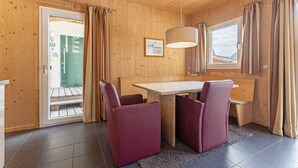 Un interior de madera con una mesa y sillas de madera, una lámpara colgante y una ventana con cortinas.