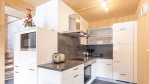 Una cocina moderna con armarios blancos, horno empotrado y tostadora.