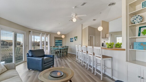 A spacious living area with a dining set, a blue sofa, and a round coffee table. - Pet Friendly | Ocean Views | Across the Road from the Beach | The Round House (Fernandina Beach)