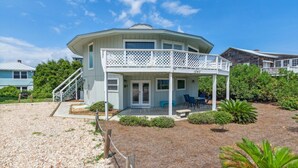 A large, light-colored house with a covered porch and a staircase leading to the entrance. - Pet Friendly | Ocean Views | Across the Road from the Beach | The Round House (Fernandina Beach)