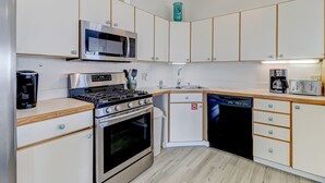 A compact kitchen with a microwave, stove, dishwasher, and a coffee maker. - Pet Friendly | Ocean Views | Across the Road from the Beach | The Round House (Fernandina Beach)