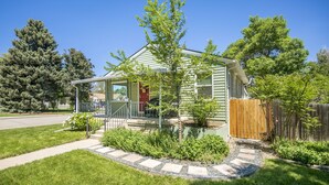 Ein eingeschossiges Haus mit Veranda, einem kleinen Garten und einem Holzzaun.