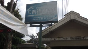 A signboard for WISMA TAMU, a university hostel, with contact details and location information. - Wisma Tamu UKSW (Salatiga)