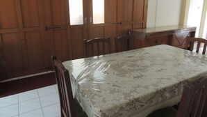 A room with a large wooden wardrobe, a dining table with chairs, and a tiled floor. - Wisma Tamu UKSW (Salatiga)