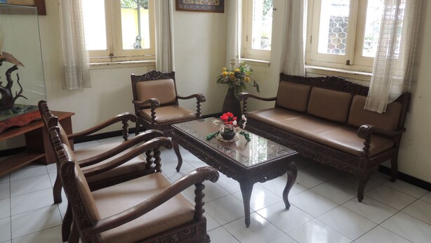 A traditional room with a sofa, two chairs, a coffee table, and a decorative vase. - Wisma Tamu UKSW (Salatiga)
