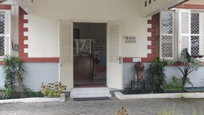 A building entrance with a sign indicating physical distancing measures. - Wisma Tamu UKSW (Salatiga)