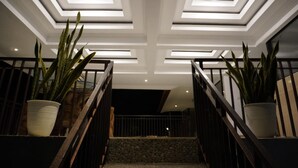 Eine moderne Treppe mit einem geometrischen Muster an der Decke und je einer Pflanztopf auf jeder Seite.