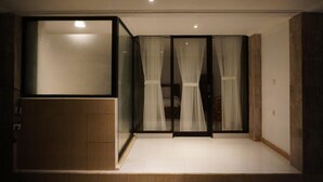 Ein Zimmer mit einer Schiebeglastür, einem Bett und einer kleinen Sitzecke.