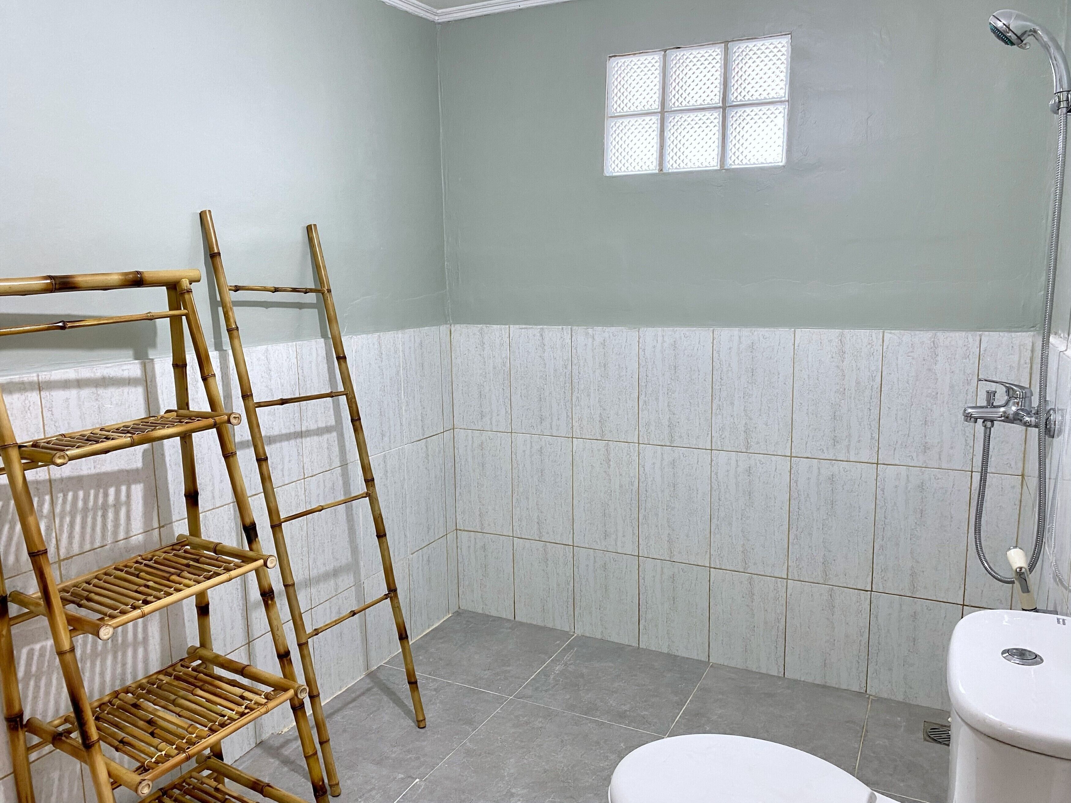 A bathroom with a bamboo shelf, a window, and a shower.
