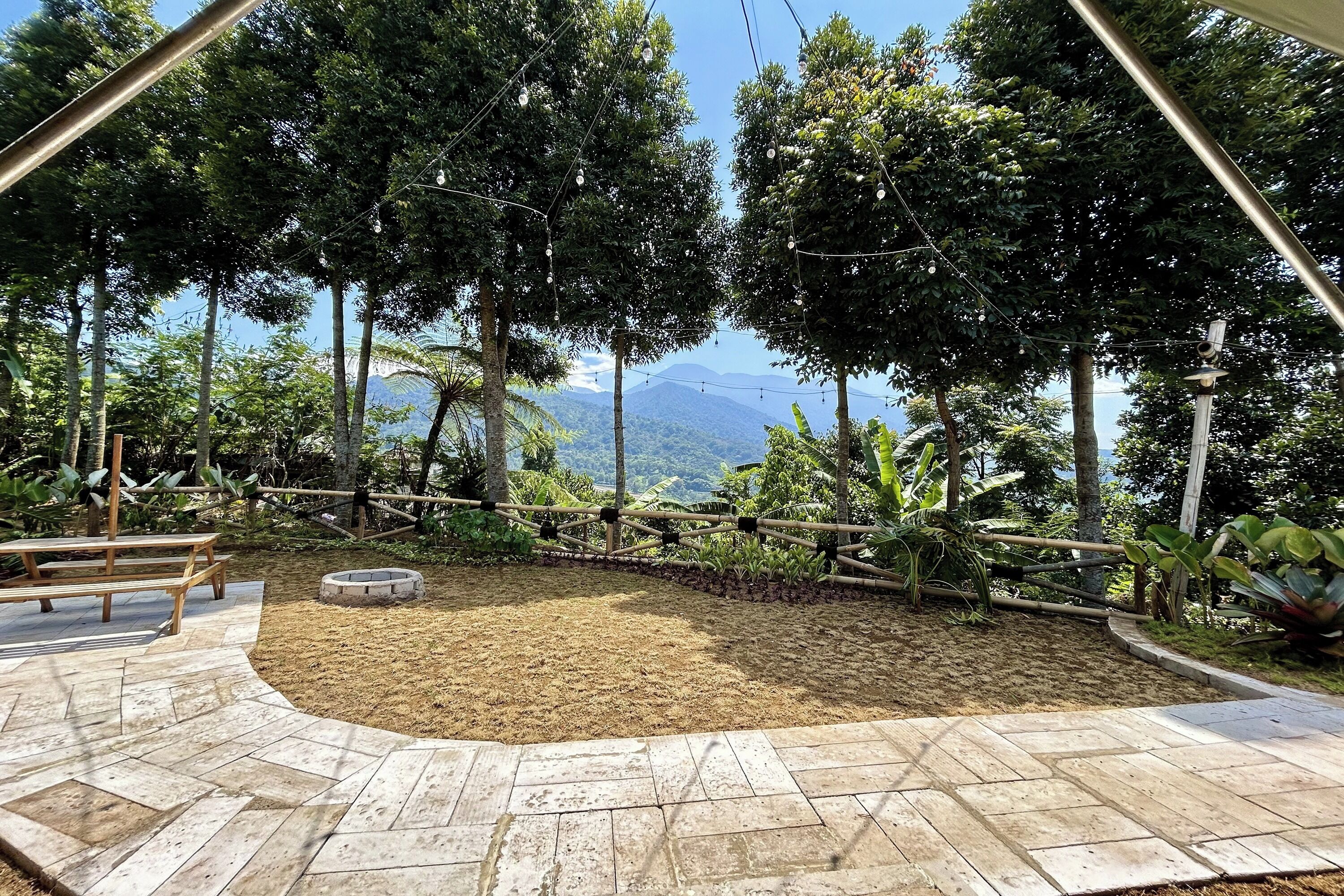 Un patio con un hoyo para fuego, bancos de madera y vistas a montañas.
