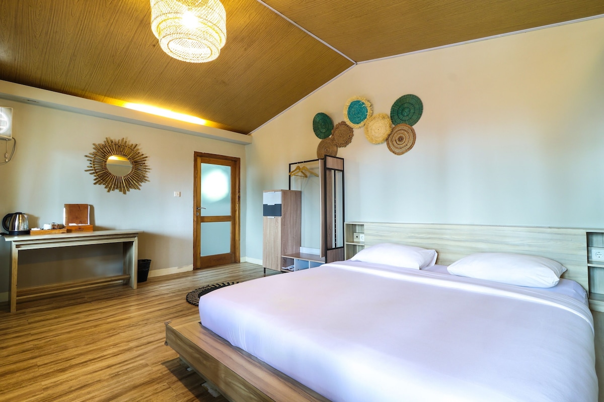 Una habitación de hotel con una cama, un escritorio, un espejo y una lámpara en el techo.