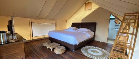 A tented room with a bed, wooden floor, and a ladder.