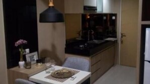 A compact kitchen with a dining area, featuring a table with chairs, a small island, and a pendant light.
