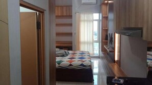 A narrow hallway leading to a bedroom with a bed, a small desk, and a built-in wardrobe.