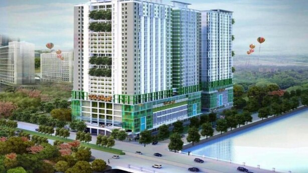 A high-rise building with multiple floors, surrounded by greenery and a water body.