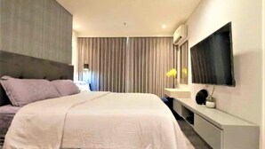 Un dormitorio moderno con una cama, un televisor montado en la pared y una mesita de noche.