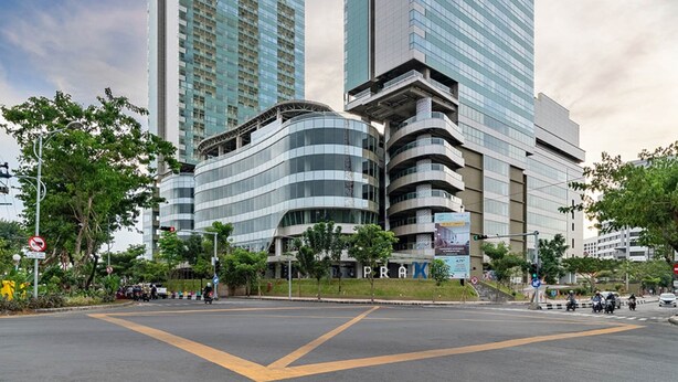Un moderno complejo de edificios con dos imponentes rascacielos, fachadas de vidrio y una sección inferior curva.