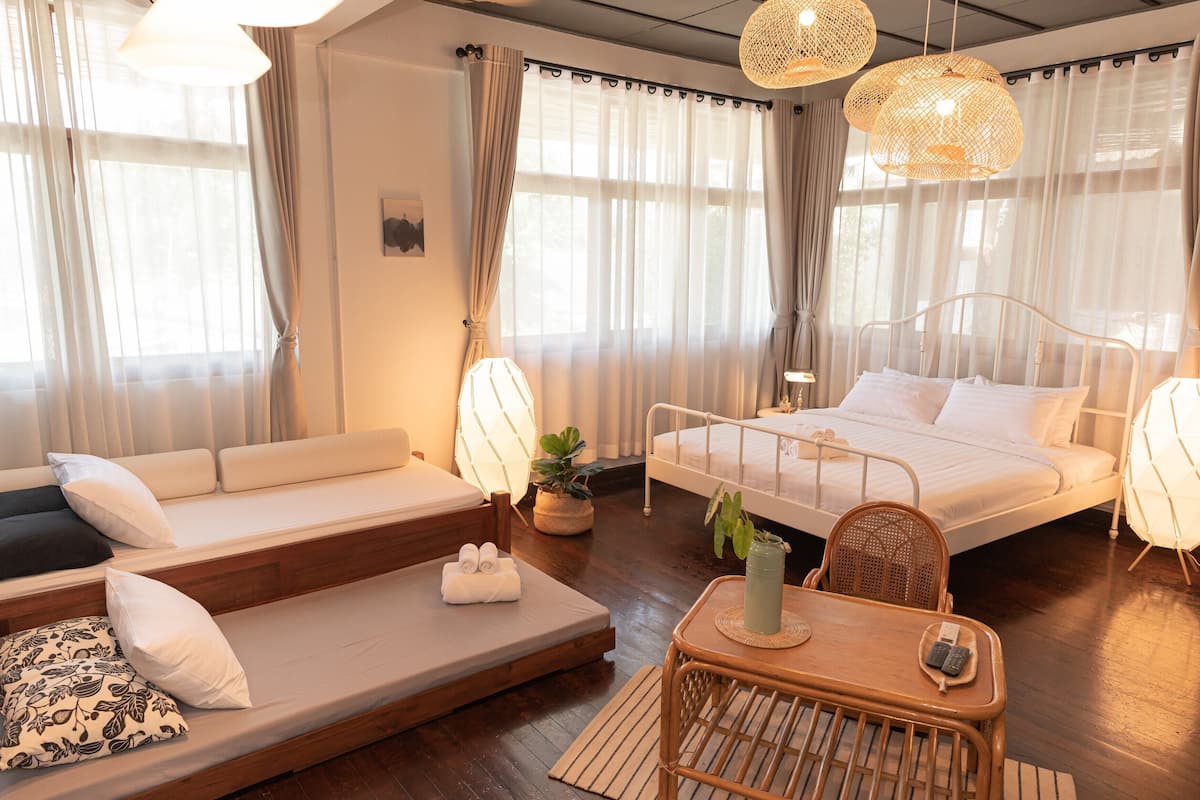 A modern hotel room with a sofa, a bed, a dining table, and a small seating area.