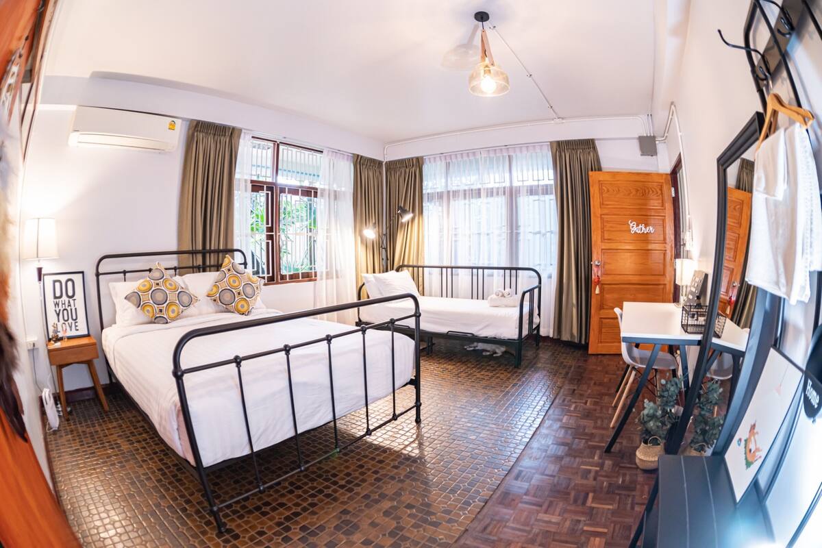 A hotel room with a bed, a desk, a chair, a mirror, and a window with curtains.