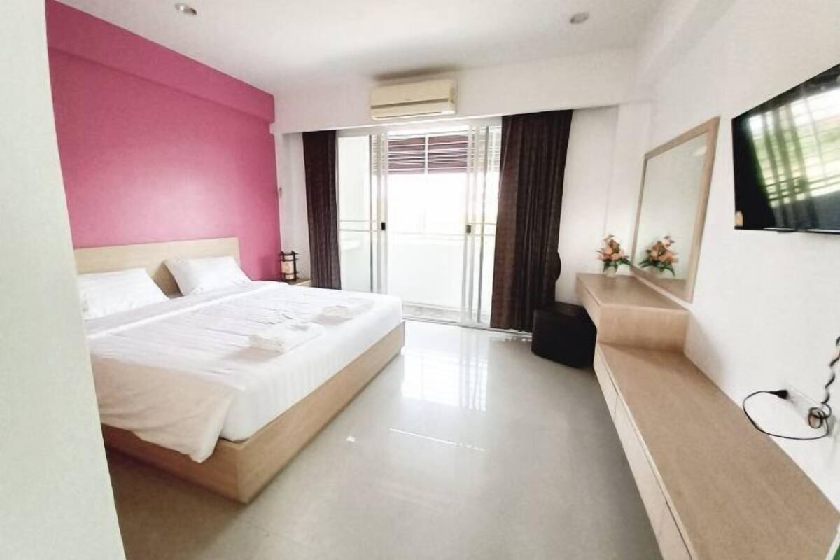 Une chambre d’hôtel avec un lit, une télévision, un bureau et une grande fenêtre avec des rideaux.