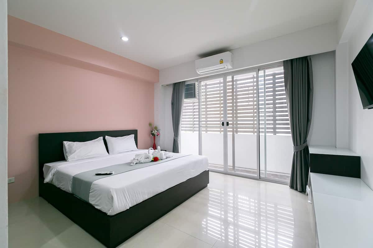 Une chambre d’hôtel moderne dotée d’un grand lit, d’un téléviseur à écran plat et d’une porte-fenêtre coulissante donnant sur l’extérieur.