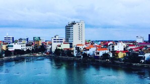 A waterfront cityscape with various buildings, including a prominent tall white building and colorful residential structures. - SIC Hotel (Dong Hoi)