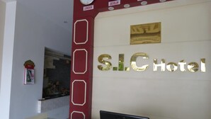 A reception desk at S.I.C. Hotel with clocks displaying different time zones, a plaque, and a laptop on the counter. - SIC Hotel (Dong Hoi)