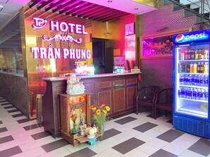 Un hotel con un neon, un frigorifero Pepsi e un altare decorativo.