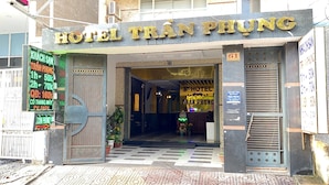 De ingang van Hotel Trần Phung, met een bord waarop kamerprijzen staan en een trap die naar binnen leidt.