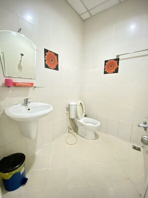Een badkamer met een wastafel, toilet en spiegel. Twee bloemenstickers op de muur.