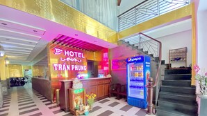 Een hotellobby met een receptiebalie, een Pepsi-koelkast en een trap.