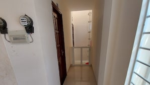 A narrow hallway with a tiled floor, a door at the end, and a window on the right. - Gianni Hotel (Ho Chi Minh City)
