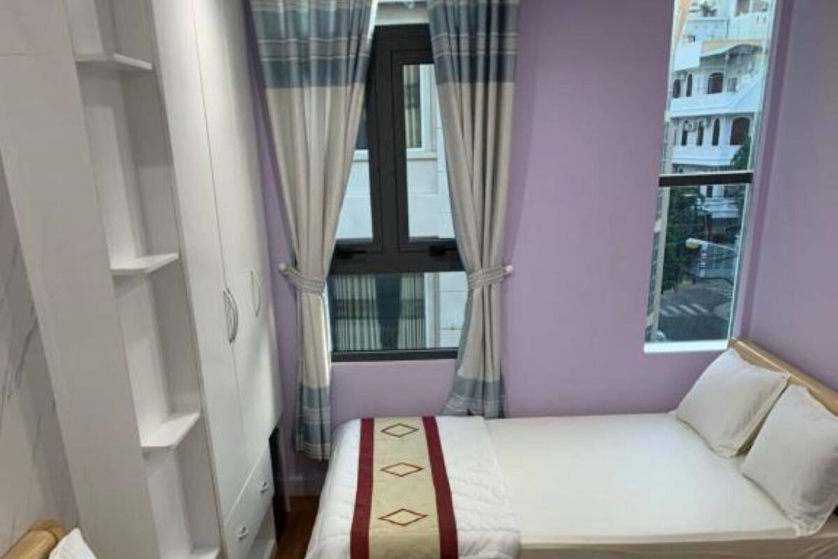 Une chambre avec deux lits, une fenêtre avec des rideaux et une armoire blanche.