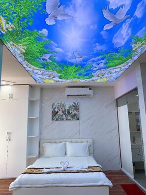 A bedroom with a mural of a blue sky and white doves, a bed with white linens, a wall-mounted air conditioner, and a shelf with a bird painting. - Hung Phat Hotel (Ho Chi Minh City)