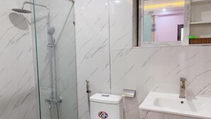 A bathroom with a glass-enclosed shower, a toilet, and a sink. - Hung Phat Hotel (Ho Chi Minh City)