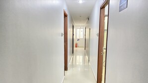 A clean, well-lit hallway with white walls and a shiny floor, leading to a door with a sign above it. - Thien Son Hotel (Ho Chi Minh City)