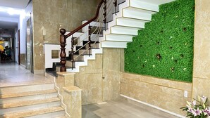 A staircase with a wooden handrail and white steps, leading to a green wall with a floral design. - Thien Son Hotel (Ho Chi Minh City)