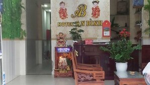 A hotel lobby with a reception desk, a clock, and a decorative wall with a floral motif. - An Binh Hotel (Ho Chi Minh City)
