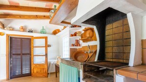 A kitchen with a wooden ceiling, a built-in oven, and shelves with dishes.