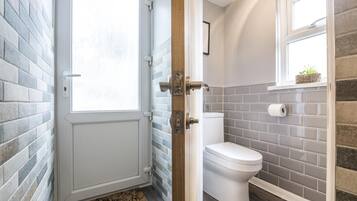 Casa de banho com sanita, janela e porta com puxador.