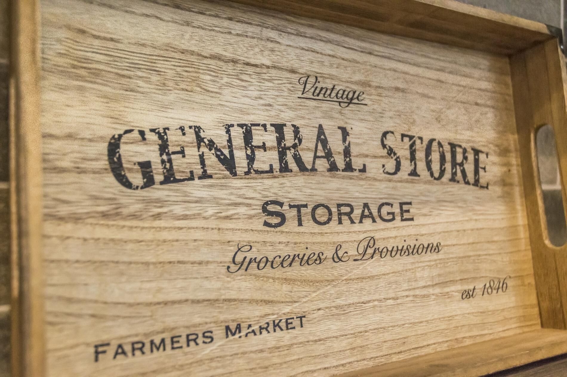Uma placa de madeira com o texto 'Vintage General Store Storage Groceries & Provisions Farmers Market est 1846'.