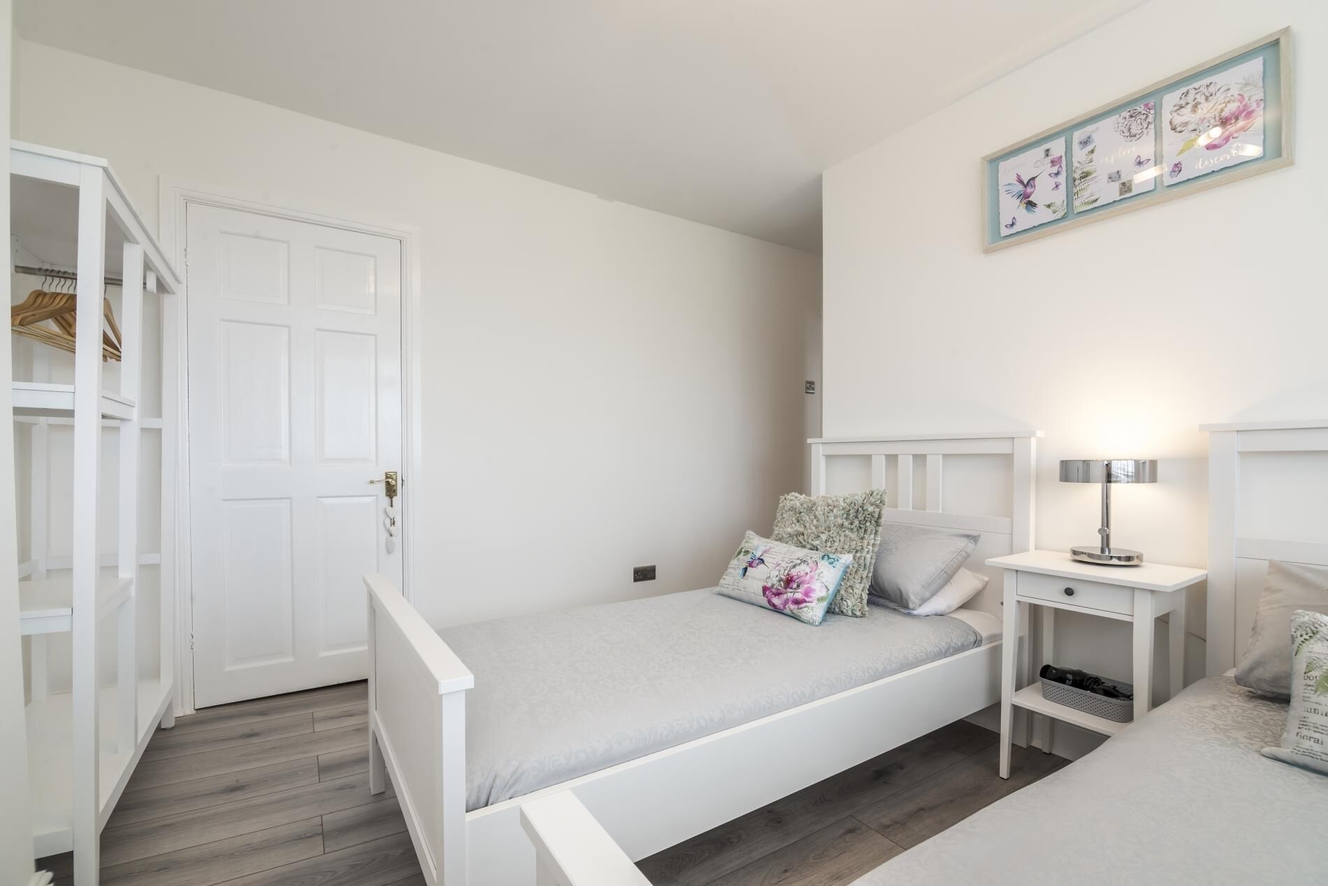 A bedroom with a single bed, a bedside table with a lamp, a wardrobe, and a framed picture on the wall.