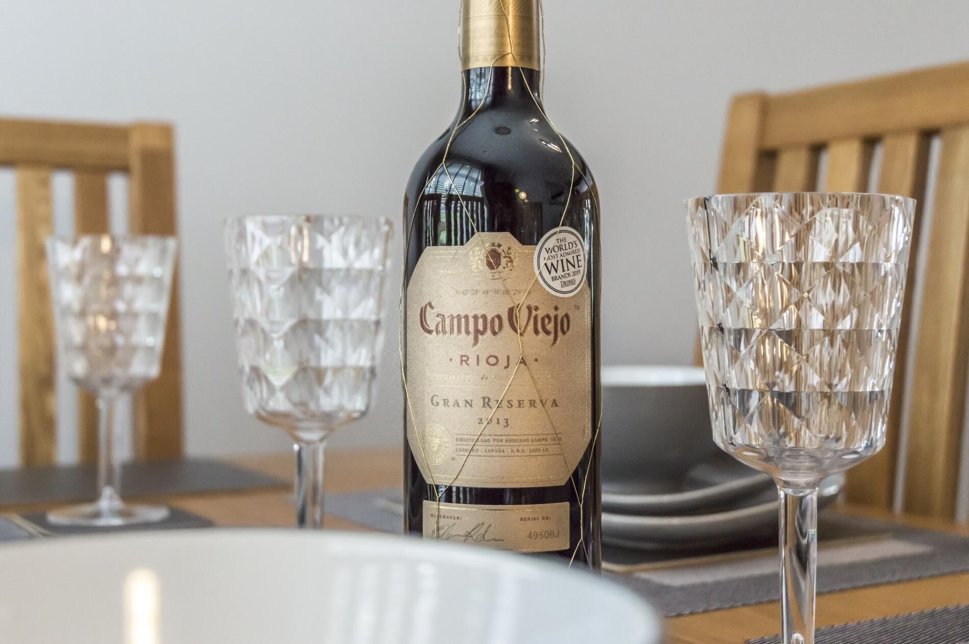 Una botella de vino Campo Viejo Gran Reserva junto con dos copas de cristal sobre una mesa.