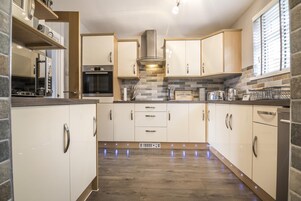 Et moderne køkken med hvide skabe, en Bosch ovn og et backsplash af grå fliser.