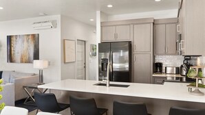 Una cocina moderna con una isla central, electrodomésticos de acero inoxidable y armarios de madera clara.