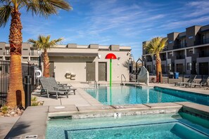 A swimming pool with clear blue water, surrounded by palm trees and lounge chairs. - Family Fun #13 by RedAwning (St. George)