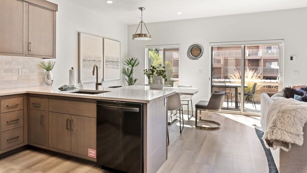 Una cocina moderna con lavavajillas, armarios de madera y un comedor con mesa y sillas.