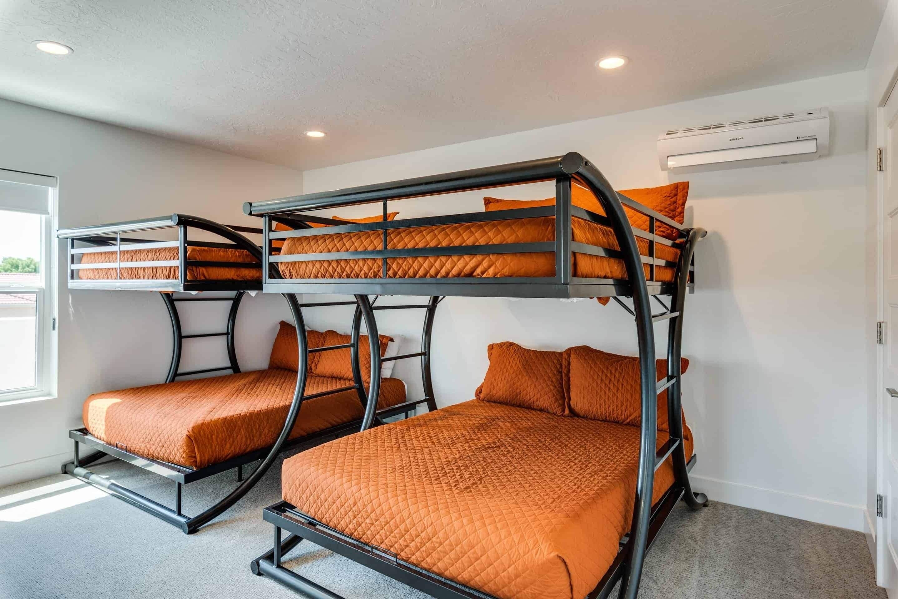 A room with bunk beds, an air conditioning unit, and a window.