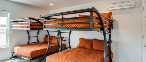 A room with bunk beds, an air conditioning unit, and a window.
